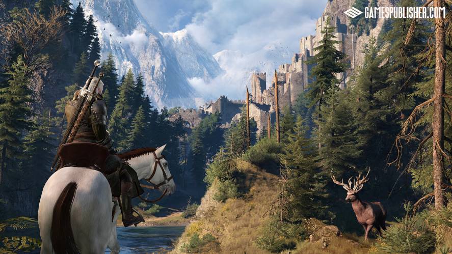 Geralt of Rivia riding Roach through a pine forest toward the ruined fortress of Kaer Morhen, surrounded by majestic snow-capped mountains and a stag standing in the foreground, in The Witcher 3: Wild Hunt.